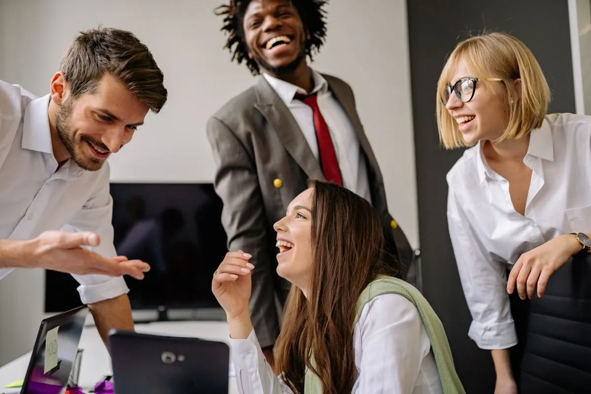 A diverse group of colleagues laughing together during a relaxed moment at work